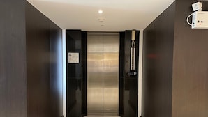 A modern elevator with a metallic finish, a wall-mounted telephone, and a control panel with a power switch. - 24 Inn at BTS Phrom Phong (Bangkok)
