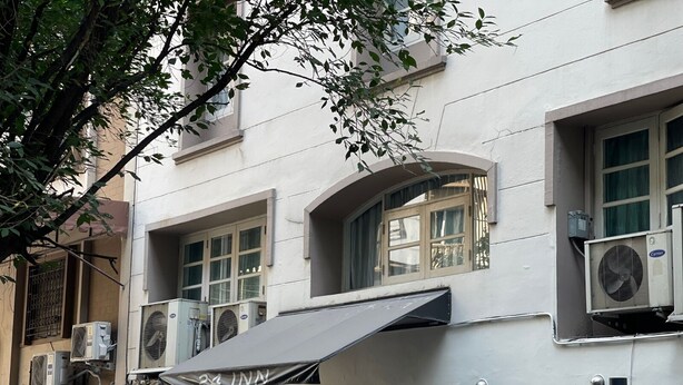 A multi-story building with air conditioning units, a storefront with a sign, and a visible door. - 24 Inn at BTS Phrom Phong (Bangkok)