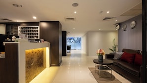 A modern hotel lobby with a reception desk, a sofa, and a coffee table. - 24 Inn at BTS Phrom Phong (Bangkok)