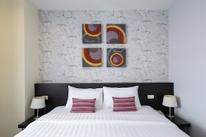 A hotel room with a bed, two nightstands, and four wall-mounted artworks. - 24 Inn at BTS Phrom Phong (Bangkok)