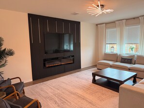 A modern living room with a flat-screen TV, a fireplace, a sofa, and a coffee table.