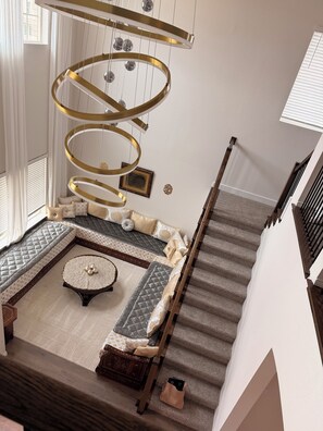 A staircase leading to a living area with a sofa, a round coffee table, and a chandelier.