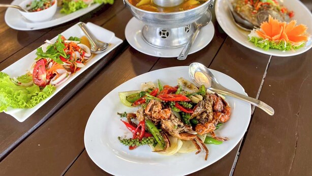 Una mesa con diversos platos, incluyendo mariscos y verduras, y una preparación para olla caliente.