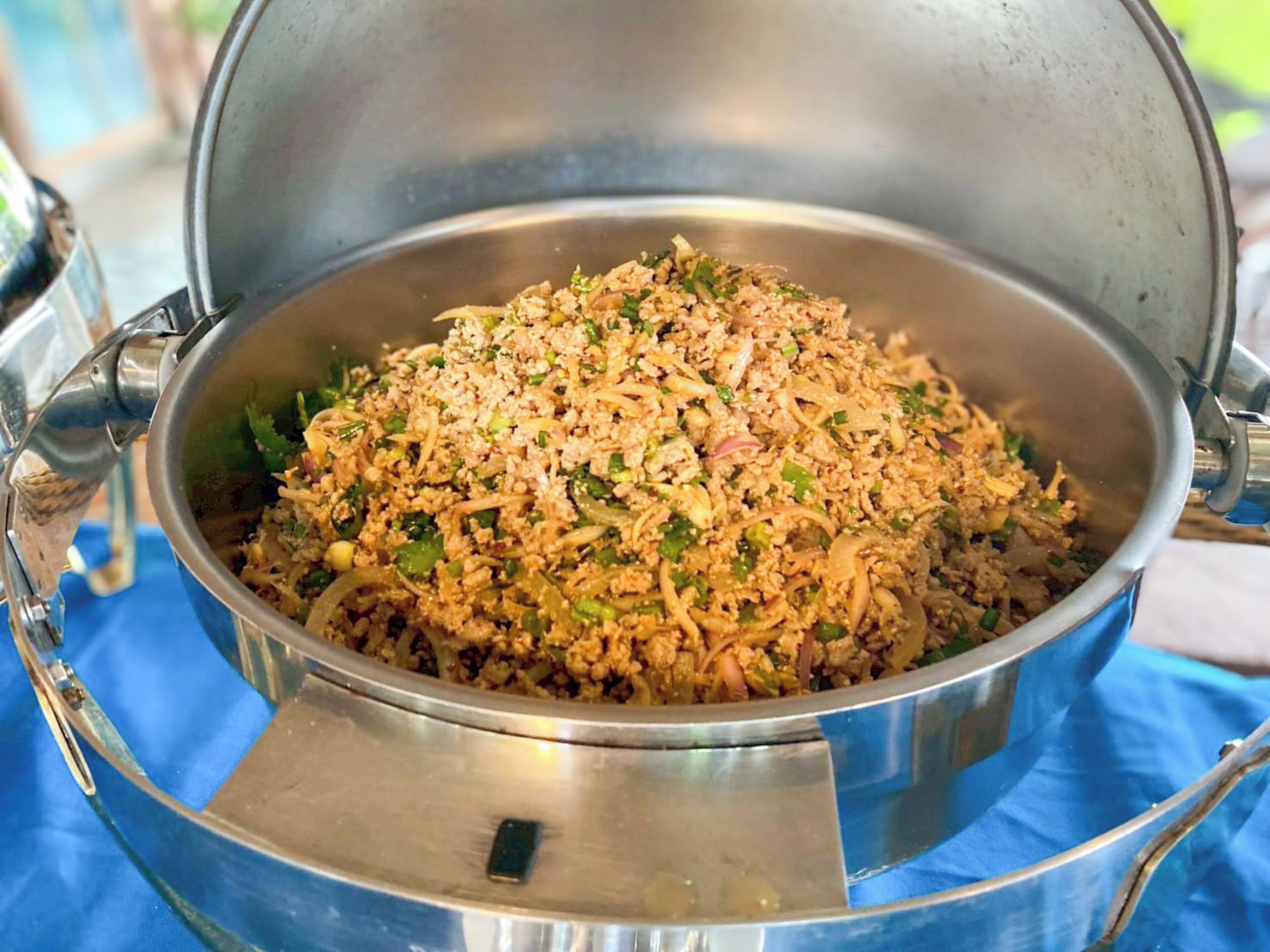Una olla metálica grande llena de un plato de comida, sobre un paño azul.