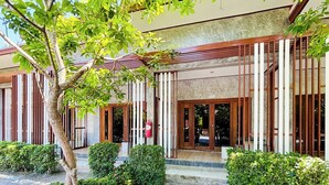 Ένα κτίριο με μοντέρνα πρόσοψη, μεγάλα παράθυρα και έναν καλά περιποιημένο κήπο.