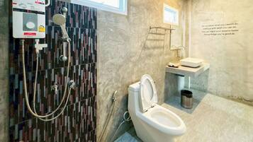 Un baño de diseño moderno, que incluye inodoro, lavabo y zona de ducha con panel de control.