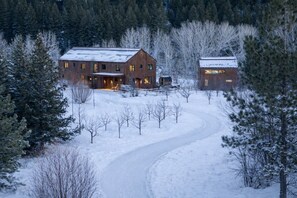 A rustic cabin with a snow-covered landscape, surrounded by trees. - The Sun Valley Rusty Barn Estate (Hailey)