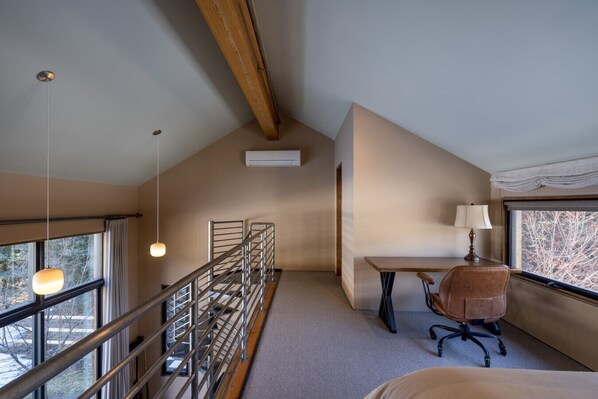 A room with a desk, chair, and a window with a view of trees.