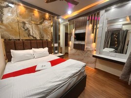 Una habitación de hotel con una cama grande, televisión, espejo y pared de mármol.