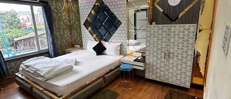 A bedroom with a bed, a desk, a wardrobe, and a mirror.