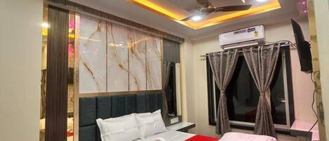 A modern hotel room with a bed, a ceiling fan, an air conditioning unit, and a window with curtains.