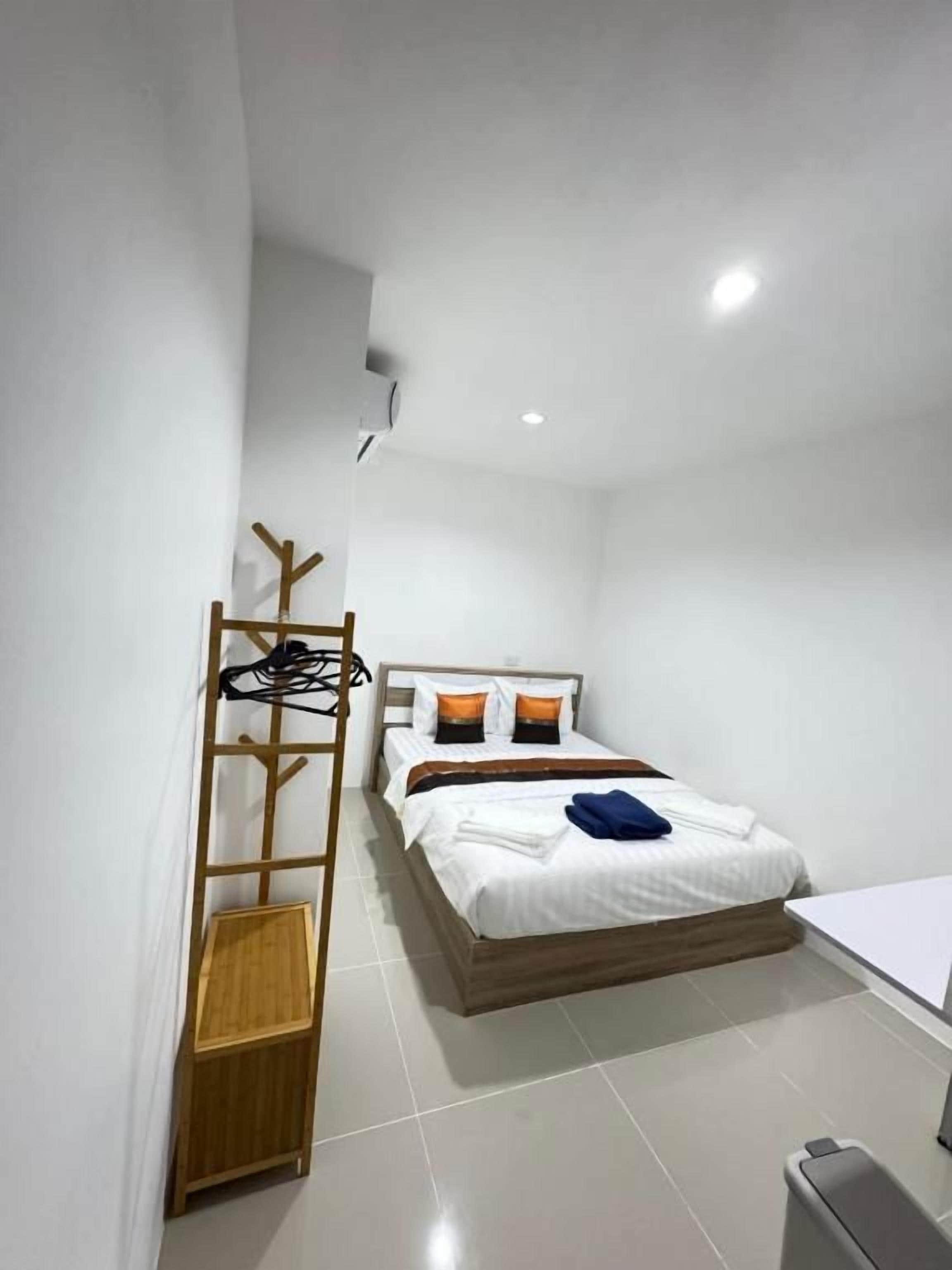 A single bed with a wooden frame, white bedding, and a small bedside table.
