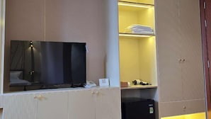 A room with a TV, air conditioning, a mini fridge, and a wardrobe. - li qiong hotel (Ho Chi Minh City)
