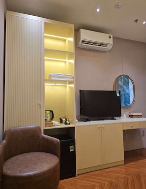 A room with a wardrobe, a flat-screen TV, a chair, and an air conditioning unit. - li qiong hotel (Ho Chi Minh Cit)