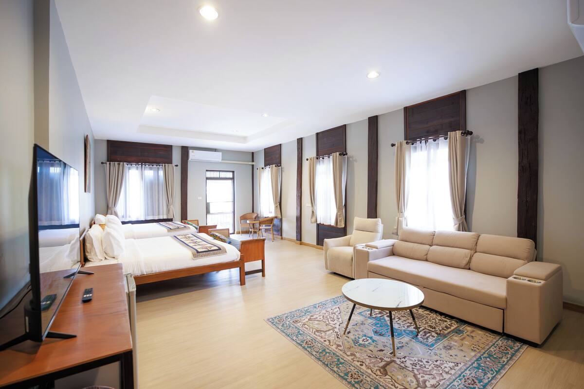 Une chambre d’hôtel avec un lit, un canapé, une télévision, un bureau et une chaise.