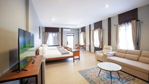 Une chambre d’hôtel avec un lit, un canapé, une télévision, une petite table et une fenêtre avec des rideaux.