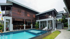 Un espace aménagé au bord de la piscine, avec un bâtiment en bois, des sièges d’extérieur et un escalier.