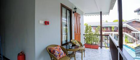 A balcony with wicker chairs, a fire extinguisher, and a door with a window.