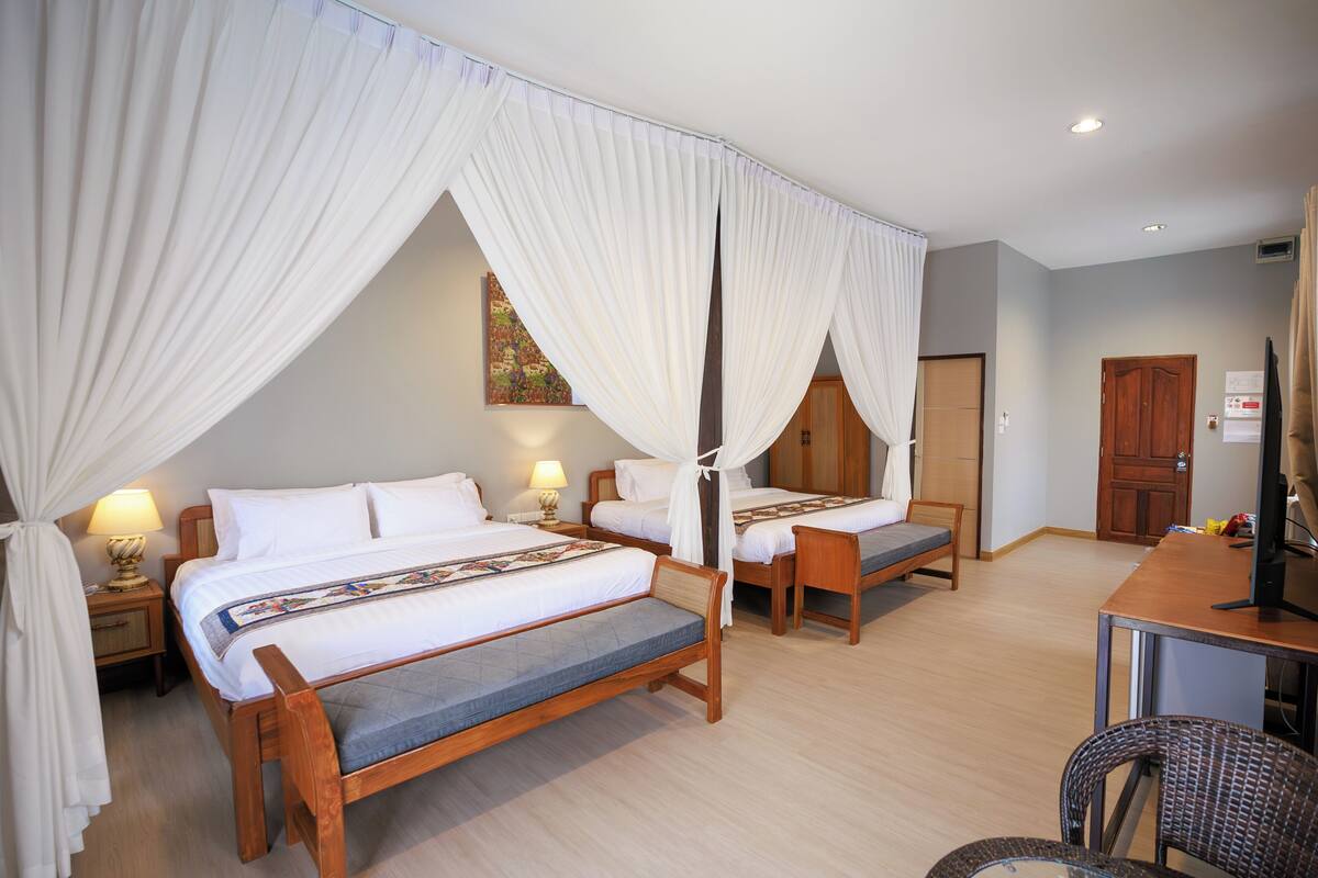 Une chambre d’hôtel avec deux lits, un bureau, une chaise, une télévision et une armoire.