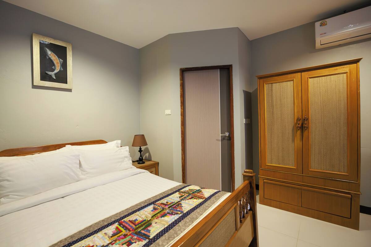 Une chambre à coucher avec un lit, une table de chevet, une lampe, une armoire et un tableau encadré au mur.