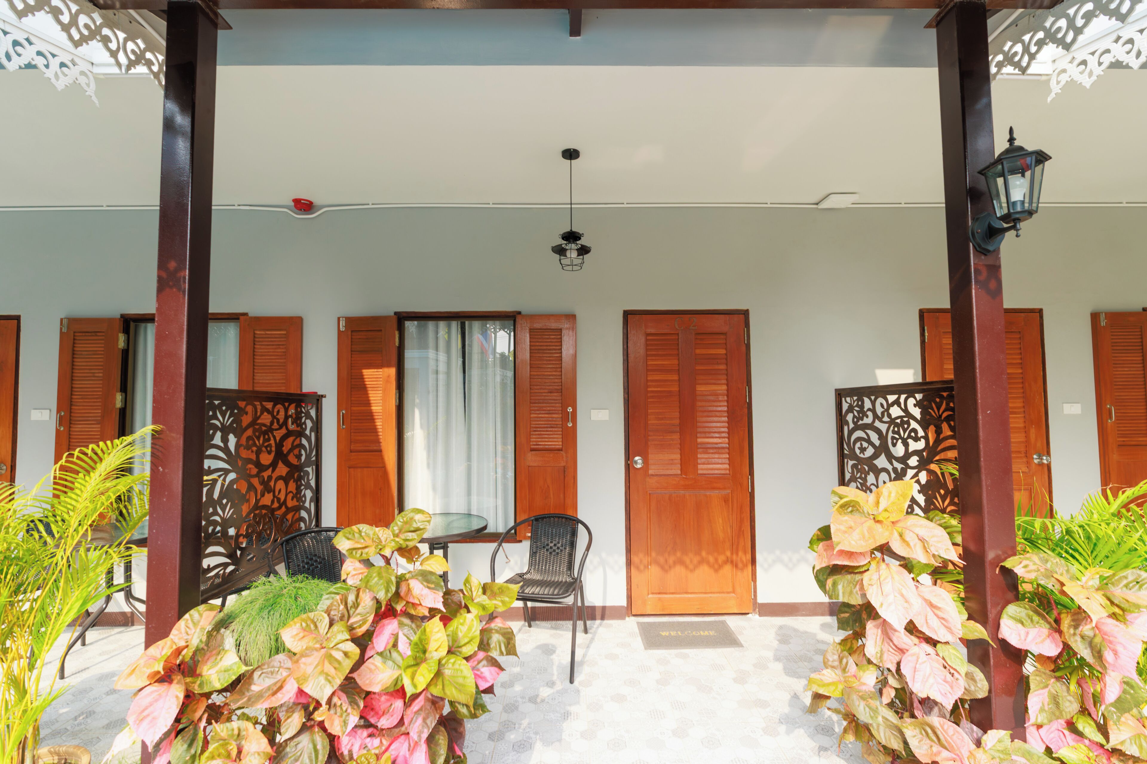 A covered outdoor area with a table and chairs, wooden doors, and decorative panels.
