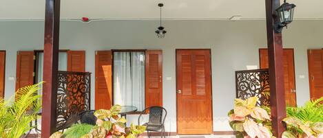 A covered outdoor area with a table and chairs, wooden doors, and decorative panels.