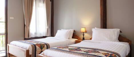 A double bed with a wooden frame and a headboard, a bedside table with a lamp, and a window with curtains.