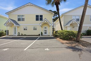 A row of yellow buildings with numbered doors, a parking lot, and a palm tree. - Chic Coastal Retreat Steps to Pool, Walk to Beach, Dining & Shopping (Miramar Beach)
