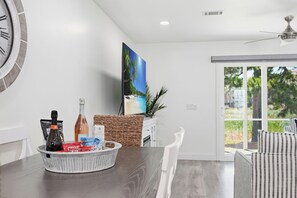 A modern kitchen with a dining area, a large window, and a wall-mounted clock. - Chic Coastal Retreat Steps to Pool, Walk to Beach, Dining & Shopping (Miramar Beach)