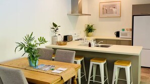 Une cuisine moderne dotée d’un îlot central, de tabourets de bar et d’une table à manger avec des chaises.