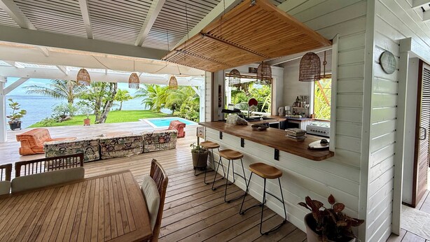 Eine Holzterrasse mit Pool, Bar und Sitzgelegenheiten.