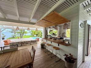 Une terrasse en bois avec une piscine, un espace bar et des sièges.