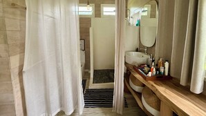 Ein Badezimmer mit Holzboden, einem weißen Waschbecken, einem Spiegel und einer Duschvorhang.