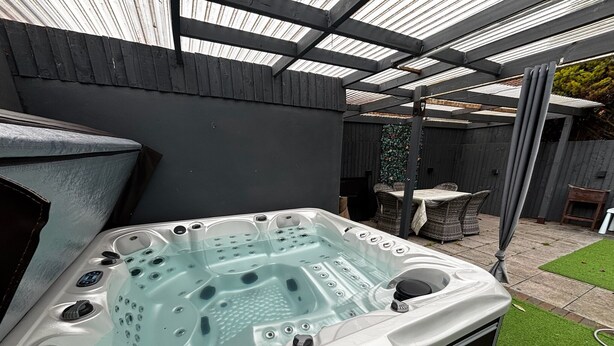 Un jacuzzi con cubierta de vidrio, rodeado por un patio con una pérgola.