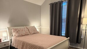 Ein Schlafzimmer mit Bett, Nachttisch, Lampe und Deckenventilator.