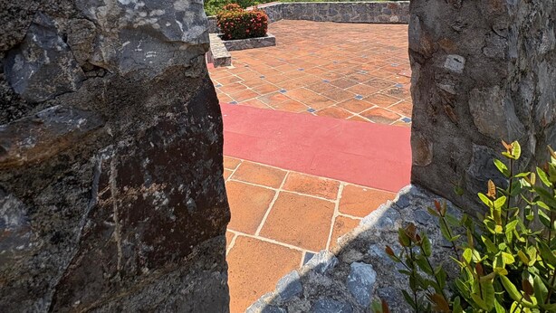 A stone archway leading to a terrace with a red floor and a view of distant buildings. - Beautiful & Spacious 2 bed 2 bath Condo in Casa Bonita.  Ixtapa ,Zihuatanejo (Ixtapa Zihuatanejo)