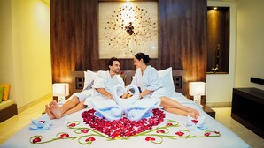 A couple in a hotel room with a bed adorned with rose petals and towels arranged in a heart shape. - Villa Campania Bali (Sukawati)