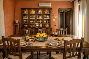 Ein Esszimmer mit Holztisch, Stühlen, einer Obstschale, Weingläsern und einem Schrank mit Geschirr.