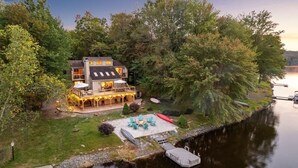 Eine Blockhütte am Seeufer mit Terrasse, Sitzgelegenheit im Freien und einer Anlegestelle.