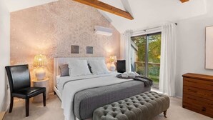 Ein Schlafzimmer mit einem großen Bett, einer Bank, einer Holzkommode und einer Wand mit dekorativem Muster.