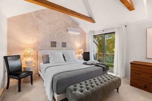 Ein Schlafzimmer mit einem großen Bett, einer Bank, einer Holzkommode und einer Wand mit dekorativem Muster.