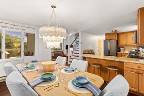 Eine moderne Küche mit Holzschränken, einem Edelstahlkühlschrank und einem Essbereich mit einem Holztisch, gedeckt für vier Personen.