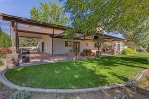A house with a covered patio, outdoor seating, and a well-maintained lawn. - Marbella Lane - Eccentric 4BR Modern Ranch Home (Reno)