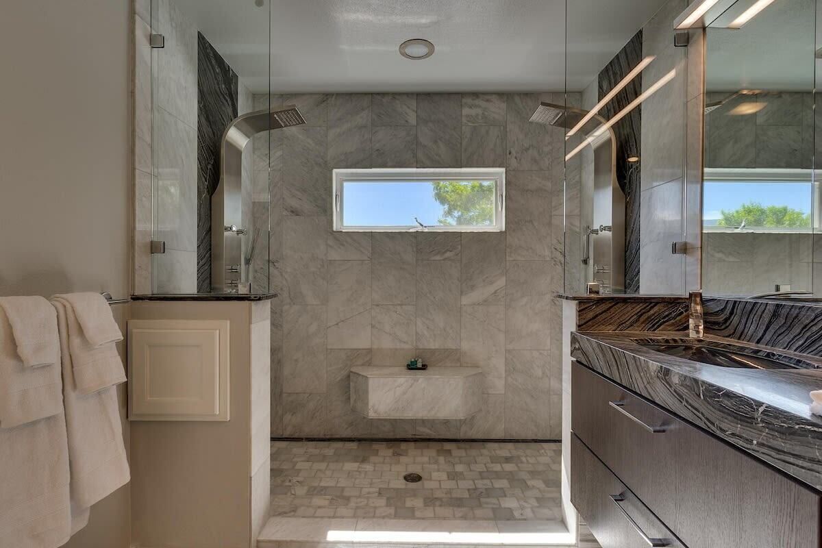 Une salle de bain moderne avec une douche, une petite fenêtre et un meuble-lavabo avec un miroir.