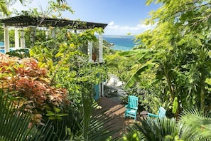 A lush garden with a gazebo, a view of the ocean, and two blue chairs. - Arc Du Soleil- Ultimate Island Living, Refreshing Salt Water Pool, Stunning Views! (Cruz Bay)