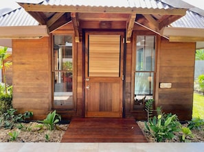 A wooden house with a central door, a small porch, and a metal roof.