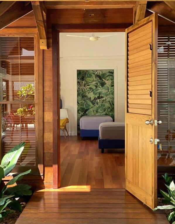 A wooden interior with a bed, a ceiling fan, and a large plant wall.