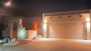 Uma casa moderna com garagem, entrada com acesso por meio de um caminho e iluminação adequada.
