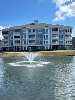 A multi-story building with balconies, a fountain in front, and a clear sky. - Lakeview Luxury: Relaxing Myrtle Beach Condo (Myrtle Beach)