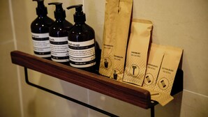 A shelf with three bottles of liquid soap and three paper bags with text. - The Golden Glow - Private Self-Check Studio In Center District 10 (Thành phố Hồ Chí Minh)